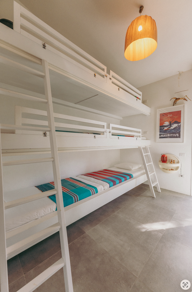 Bunk bed with colorful mattress in a room with a ladder and a light fixture.