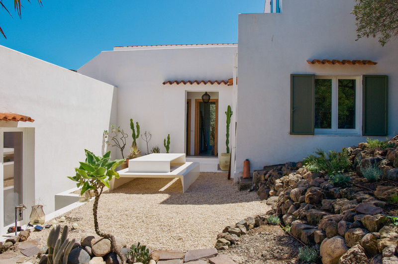 White house exterior with a patio area and cacti under a clear blue sky.