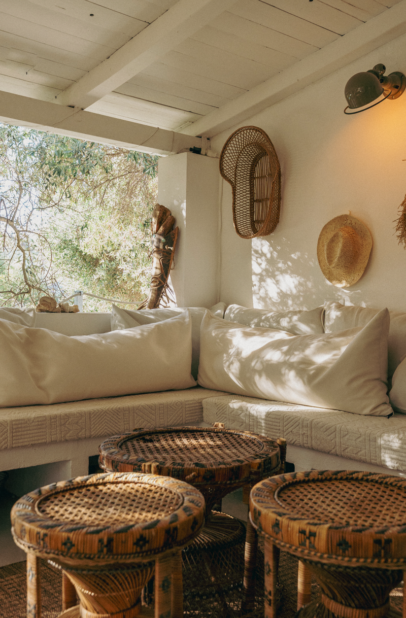 Cozy indoor setting with a white sofa, wicker stools, and decorative hats.