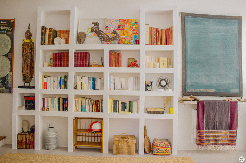 White bookshelf with various items including books, a vase, and a painting in a room.