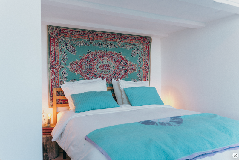 Bed with turquoise bedding and a decorative headboard in a bedroom setting.