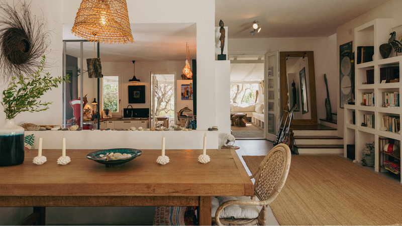 Dining room with wooden table, wicker chair, and bookshelf.