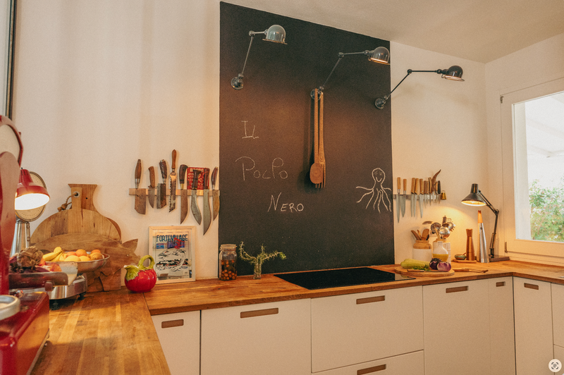 Modern kitchen with a blackboard wall, utensils, and appliances.