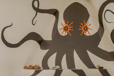 Living room with a large octopus wall mural and a beige armchair.