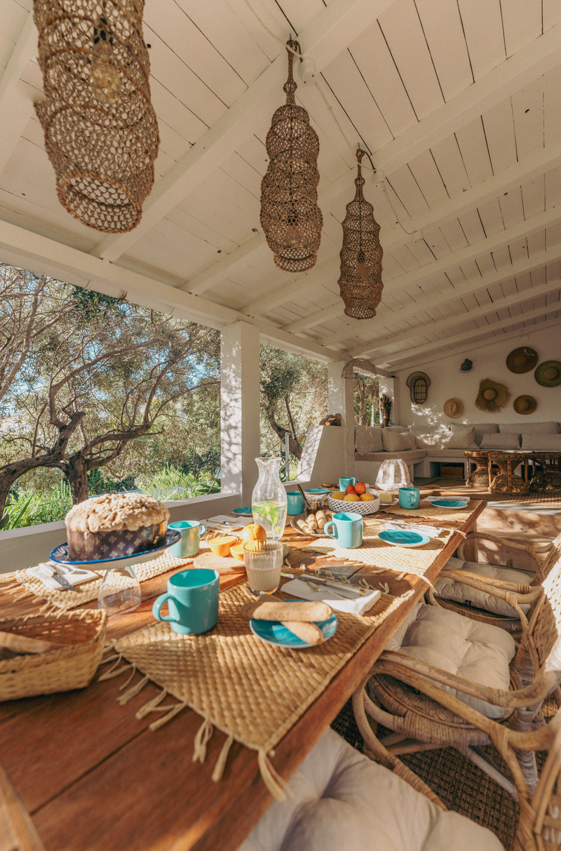 Outdoor dining area with wicker furniture and a view of trees.