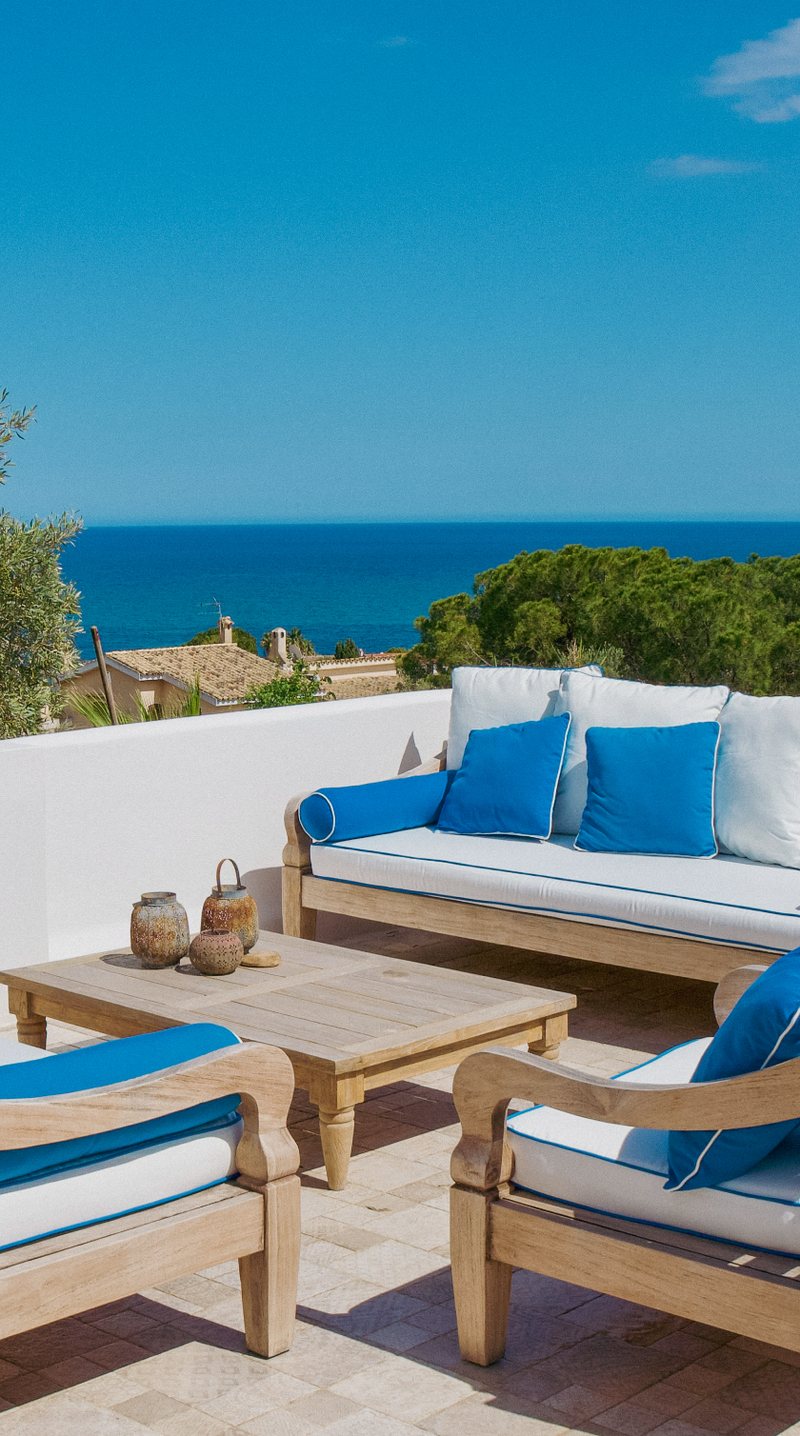 Outdoor patio set with blue cushions and a view of the ocean.