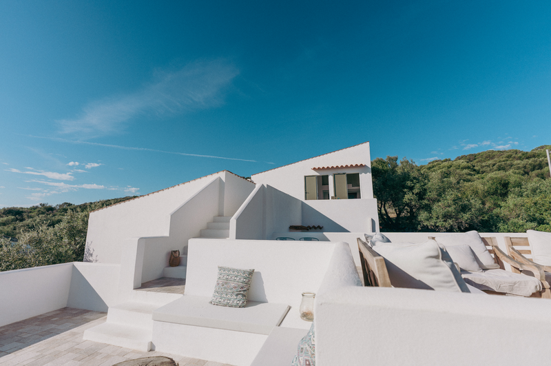 White architectural structure with outdoor seating area under a clear blue sky.