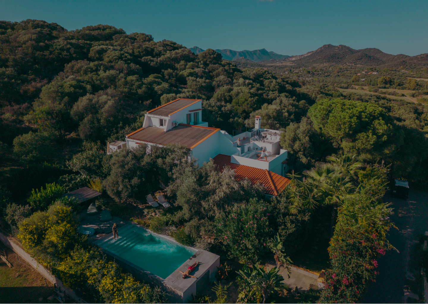 Aerial view of a villa with a pool surrounded by lush greenery.