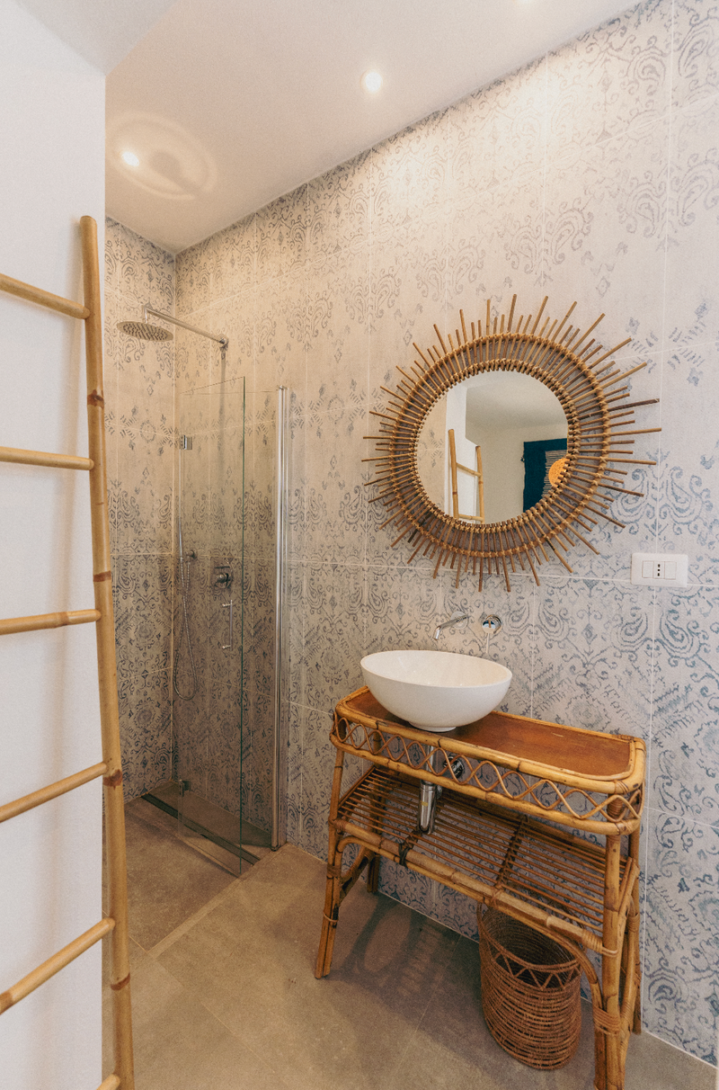 Bathroom with rattan vanity, round mirror, and shower area.