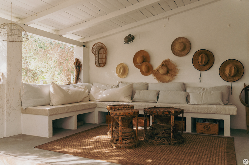 Cozy living room with a sectional sofa, wicker chairs, and hats on the wall.