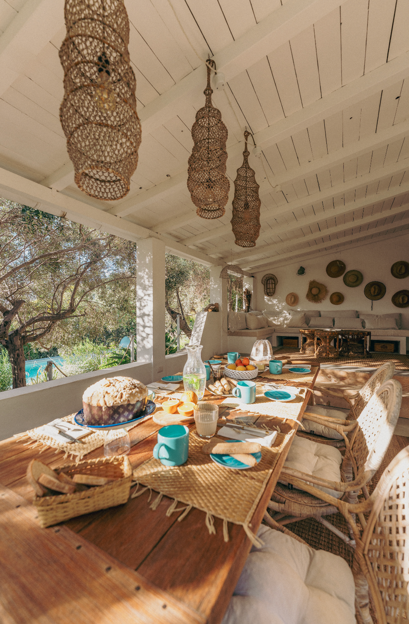 Dining area with wooden table, wicker chairs, and decorative elements in a bright room.